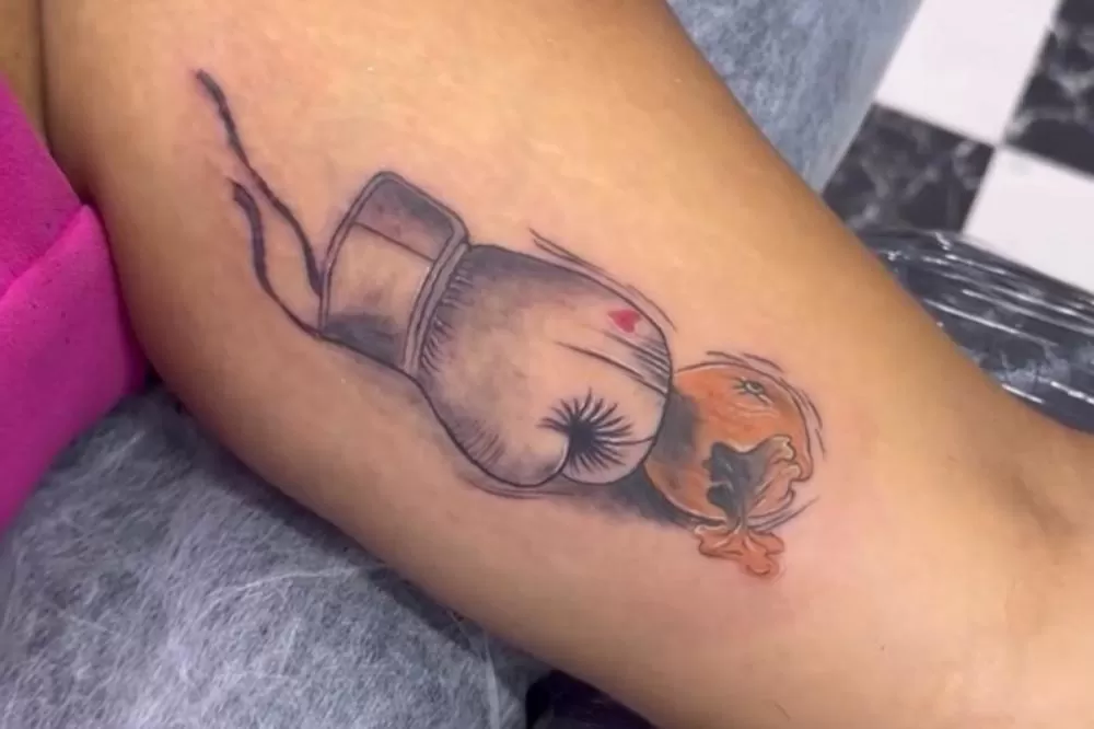 Mulher filmada em confusão com PM após show no Recife faz tatuagem de luva de boxe socando laranja